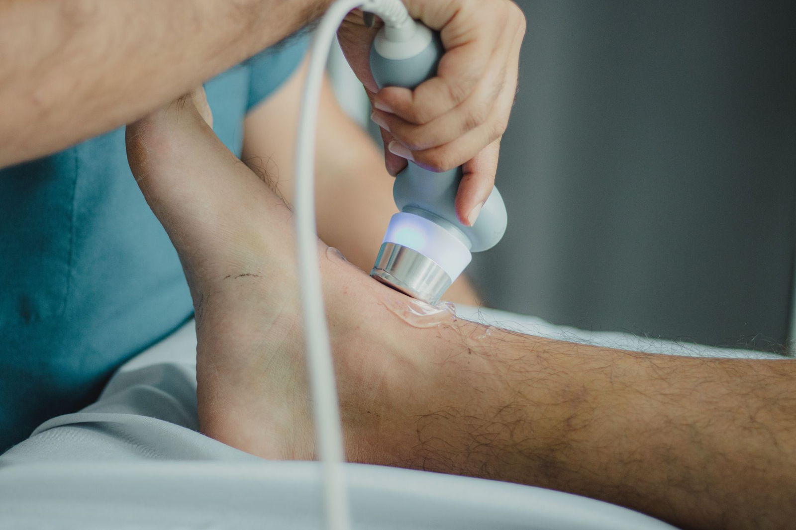 Cabezal de ultrasonido terapéutico aplicado con gel sobre la rodilla de un paciente